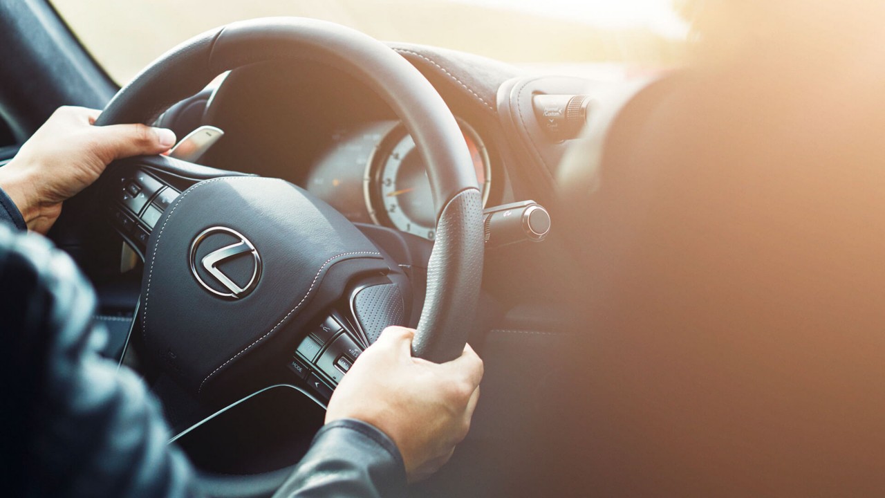 A man sat on the boot of the Lexus NX on the coast